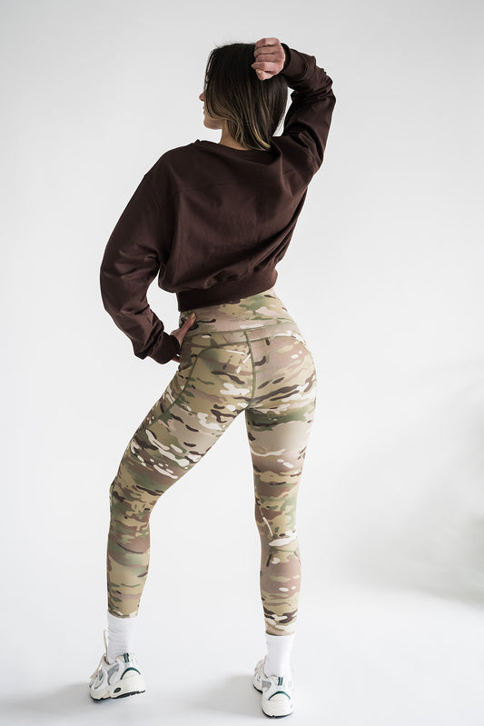 Woman wearing brown Cropped Crew sweatshirt with MULTICAM leggings full body back side view