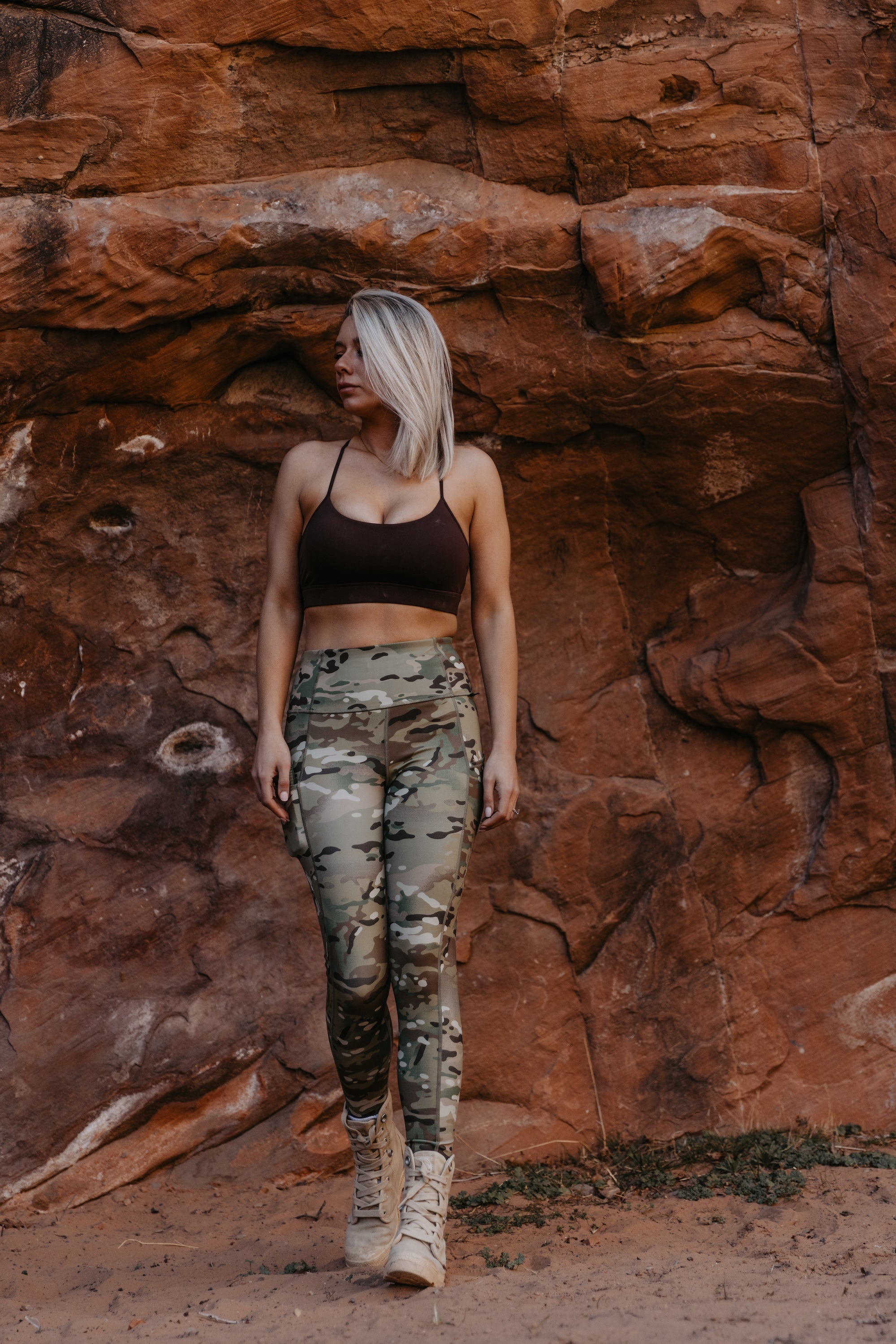 Woman wearing Fit By Nature Multicam leggings standing against red rock desert backdrop